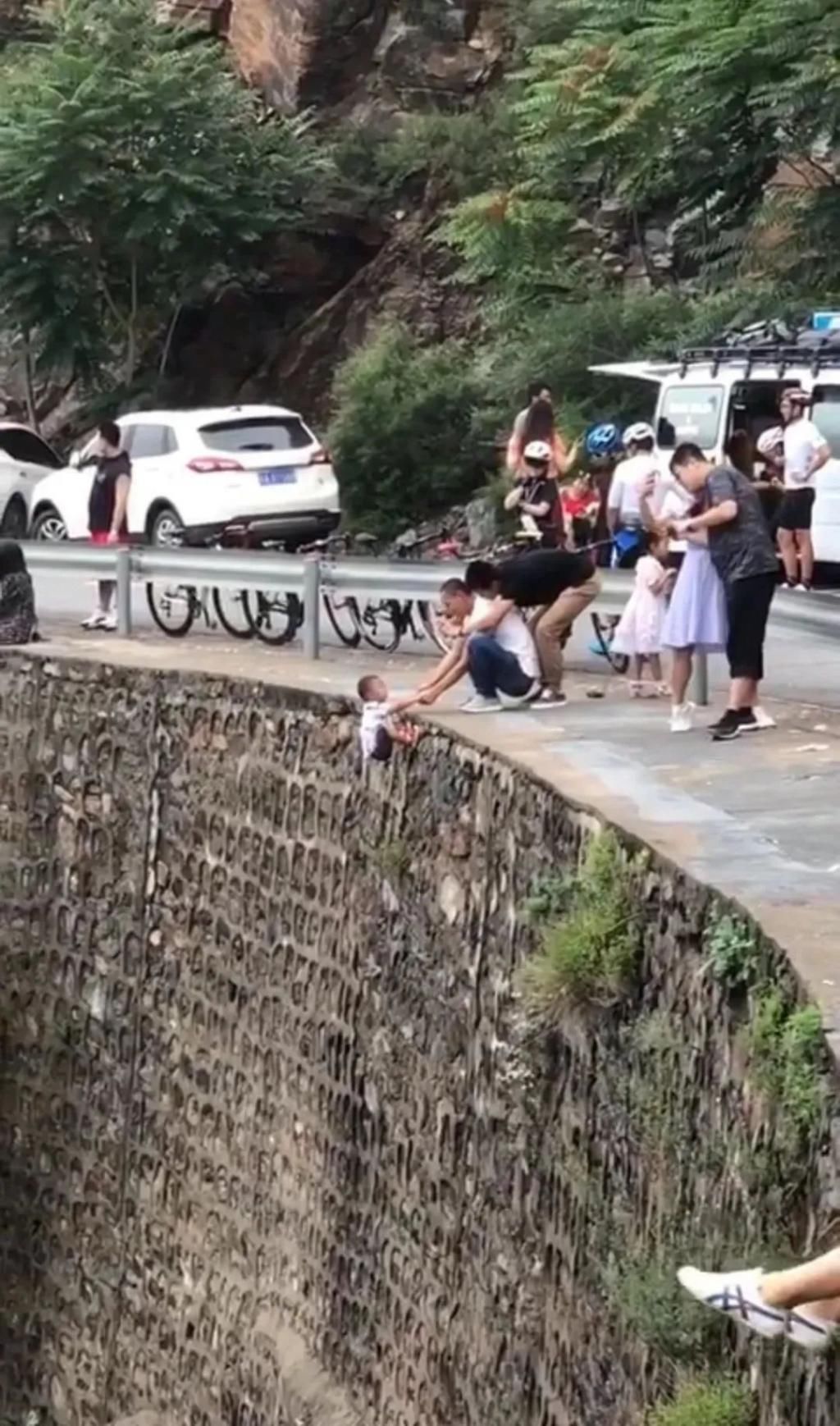 视频|这家长太不靠谱竟抓着孩子挂峭壁上拍照，脚下就是悬崖